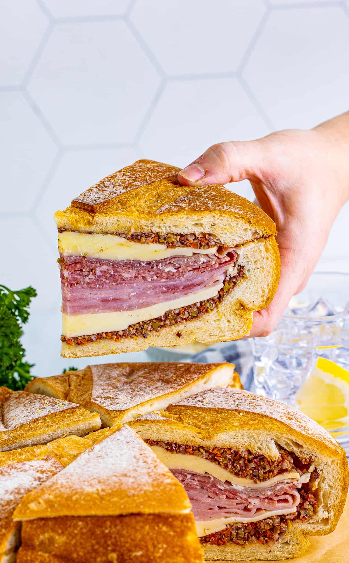 Hand holding up one wedge of the sandwich showing the layers inside.