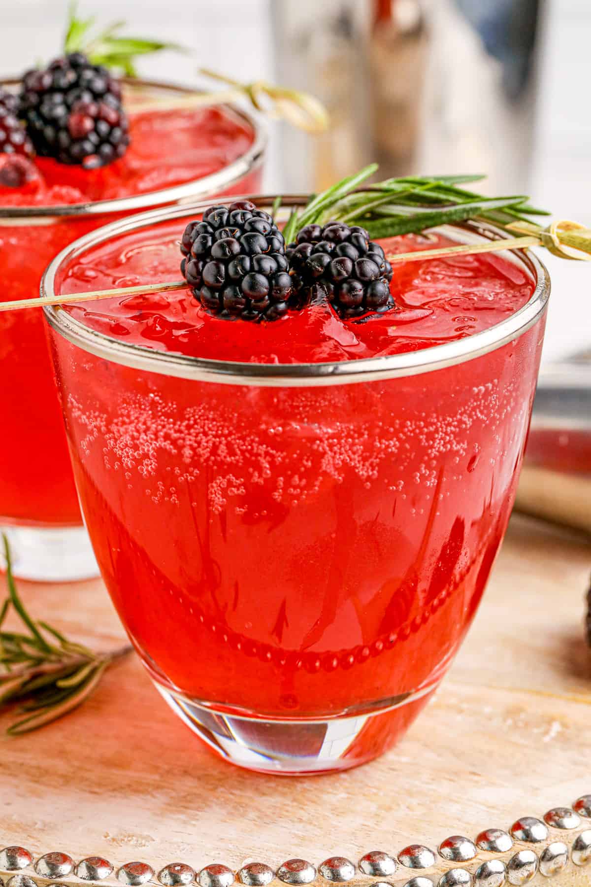 Blackberry Bourbon Smash in metal rimmed glass on wooden tray topped with blackberries and thyme.