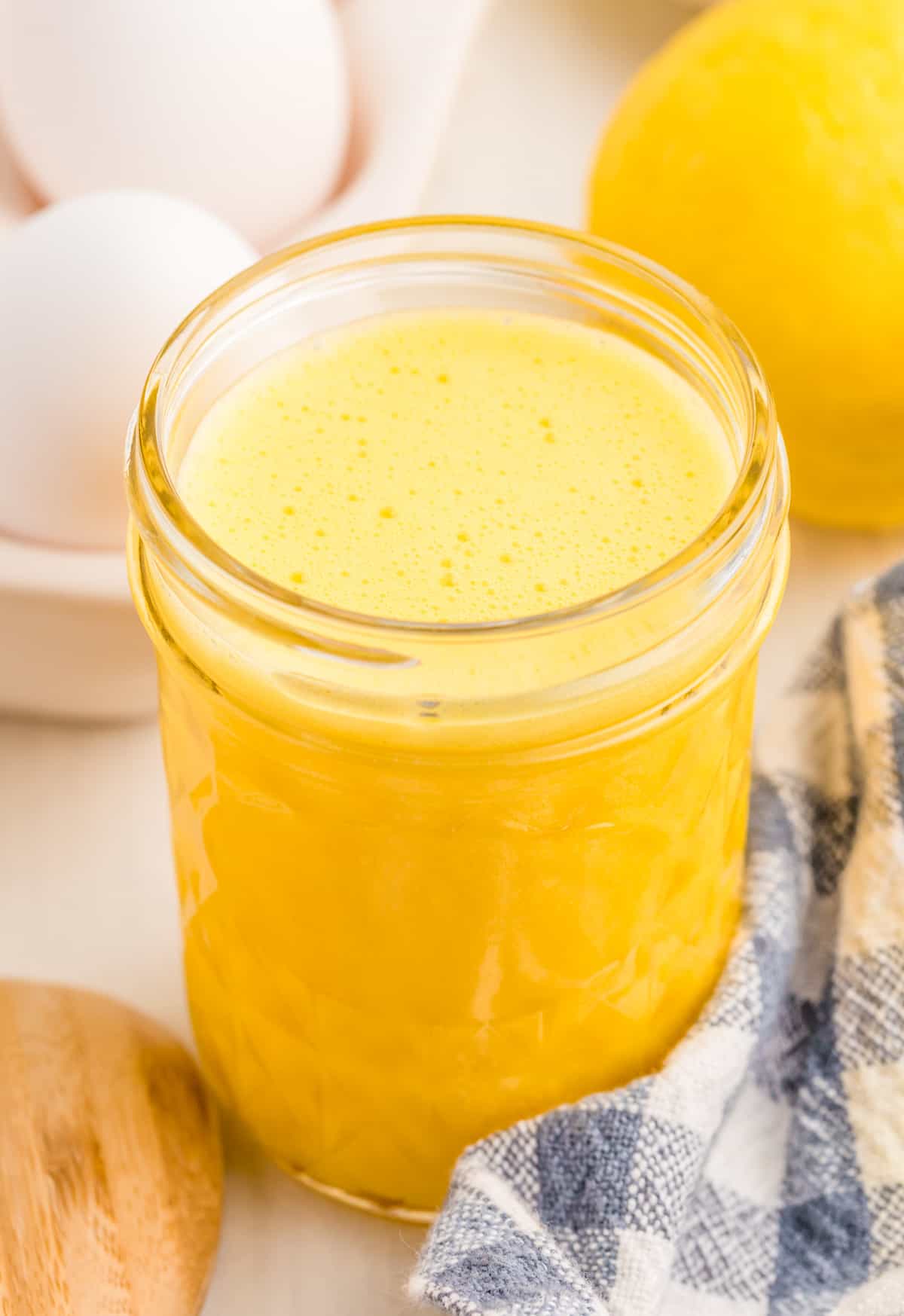 Hollandaise Sauce in mason jar with eggs and lemon in background.