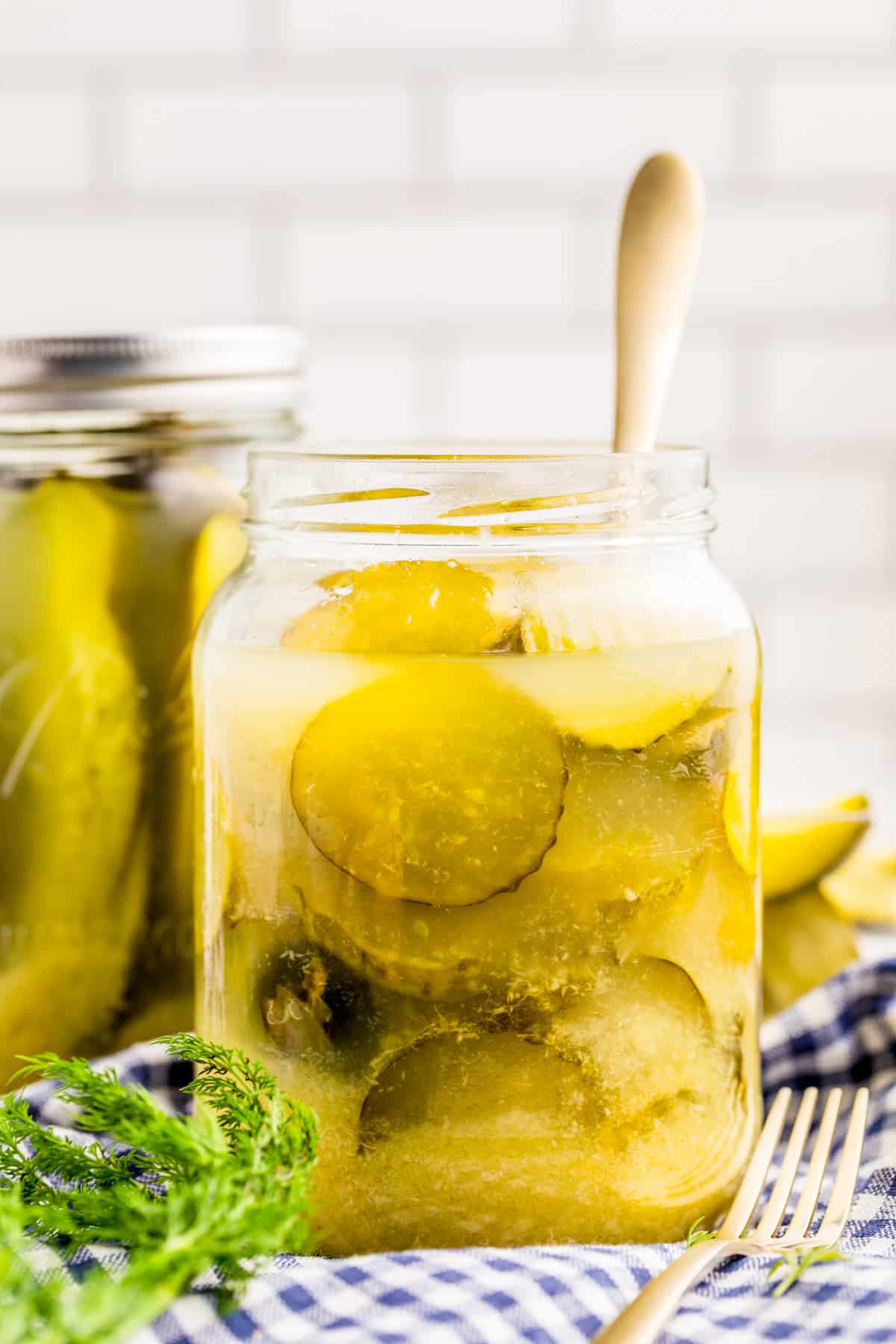 Horseradish Pickles in jar with fork and a jar of pickle spears in background.