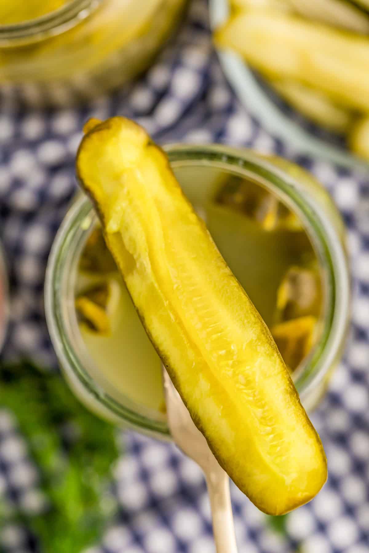 Fork holding up a pickle spear out of the jar.