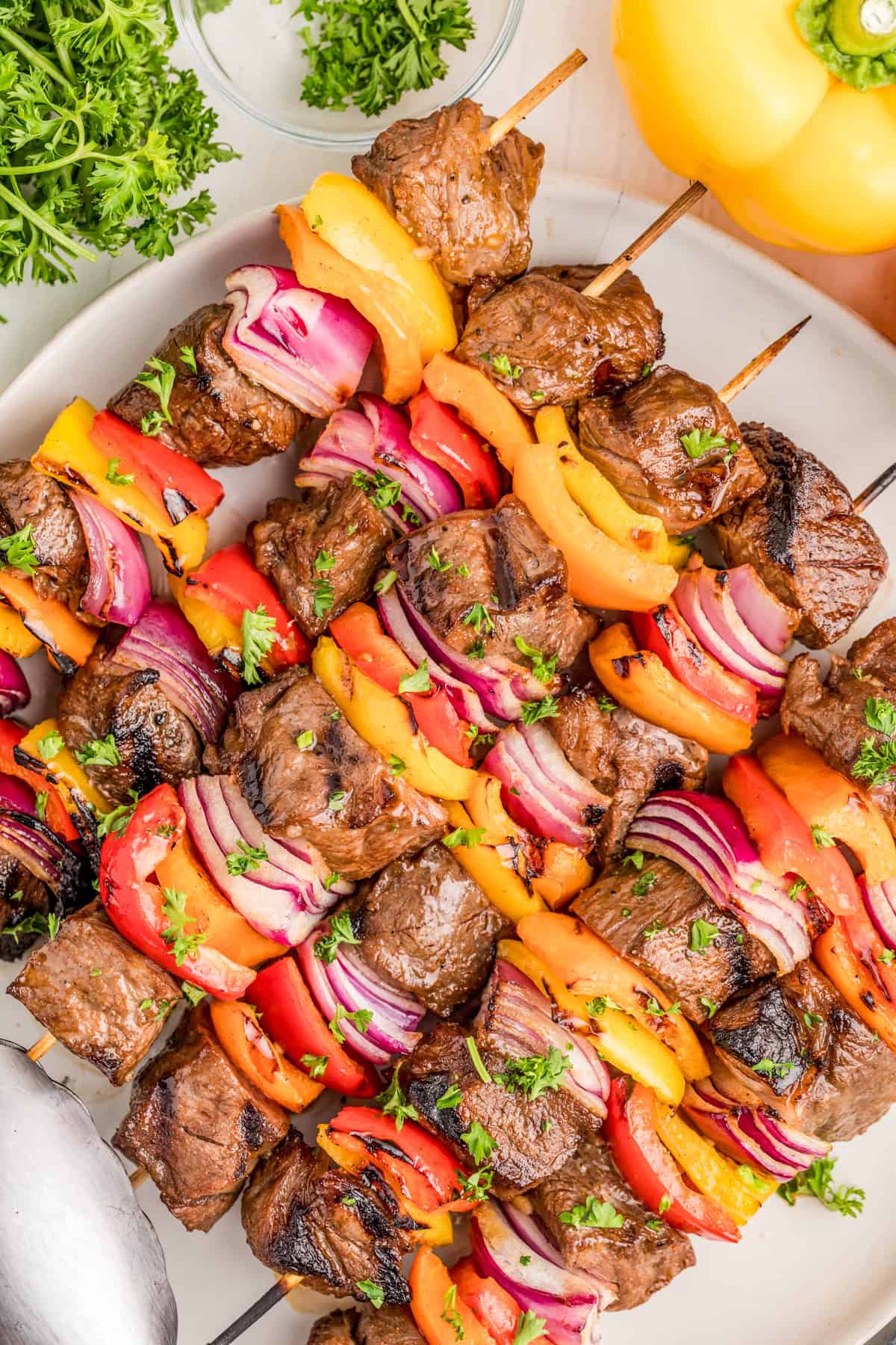 Steak Kabobs on white plate topped with parsley.