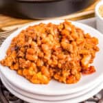 Close up square image of beans on stacked white plates.