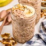Close up square image of Banana Overnight Oats in jar topped with sliced bananas, chia seeds and chopped walnuts.