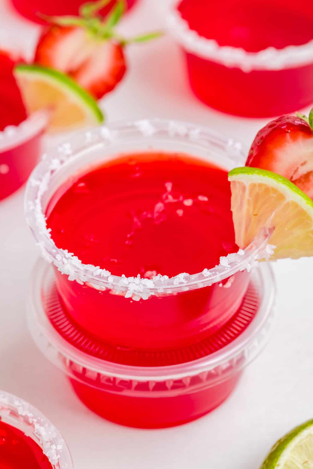 Two stacked Strawberry Margarita Jello Shots top one showing the salt, lime and strawberry garnish.