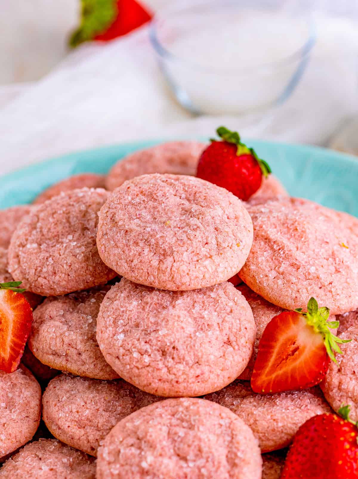 Strawberry Sugar Cookies on a blue plate stacked on top of one another with strawberries on top of cookies.