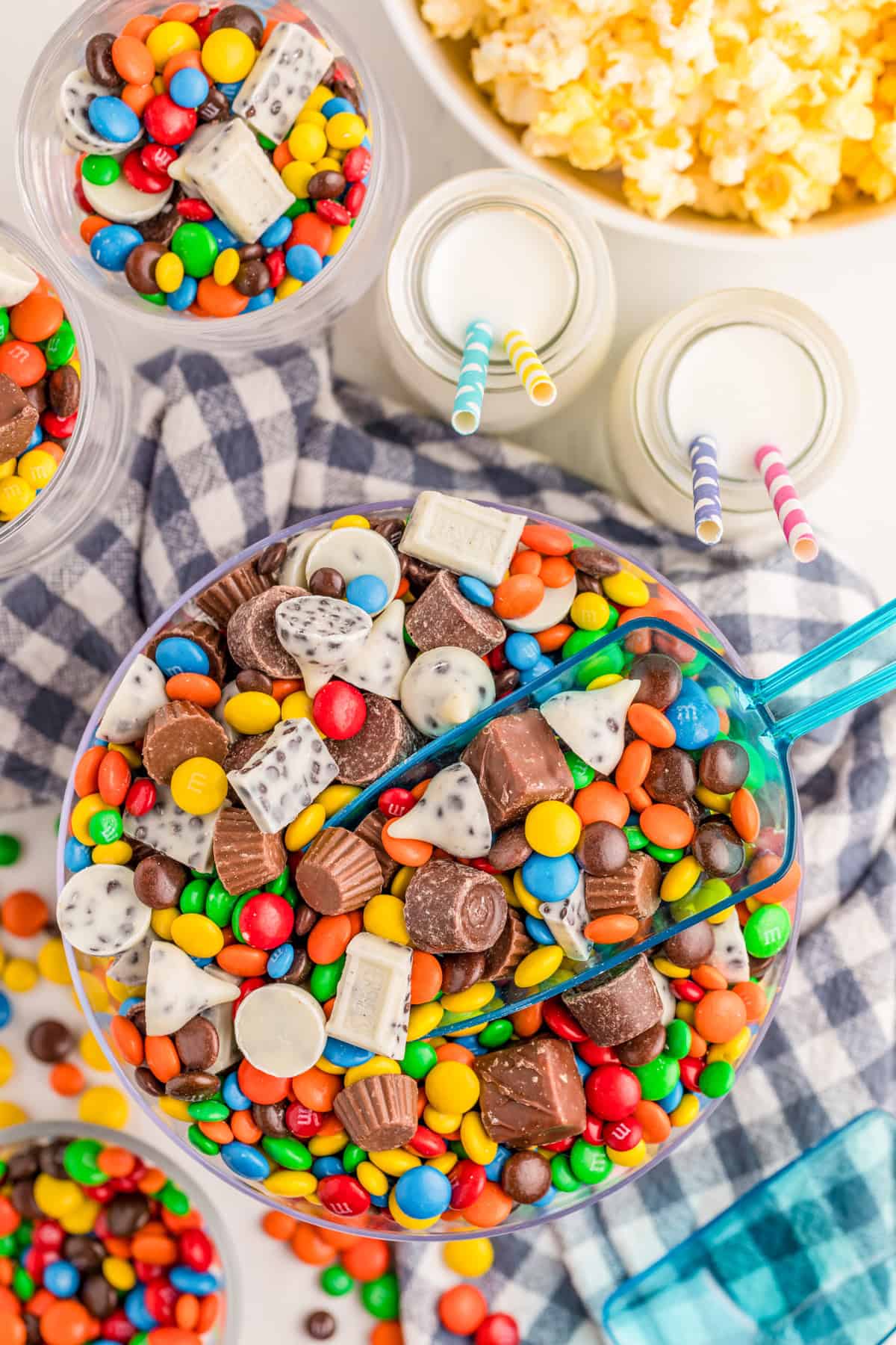 Overhead of salad in glass bowl with a blue plastic scoop in the bowl surrounded by milk, popcorn and more candy.