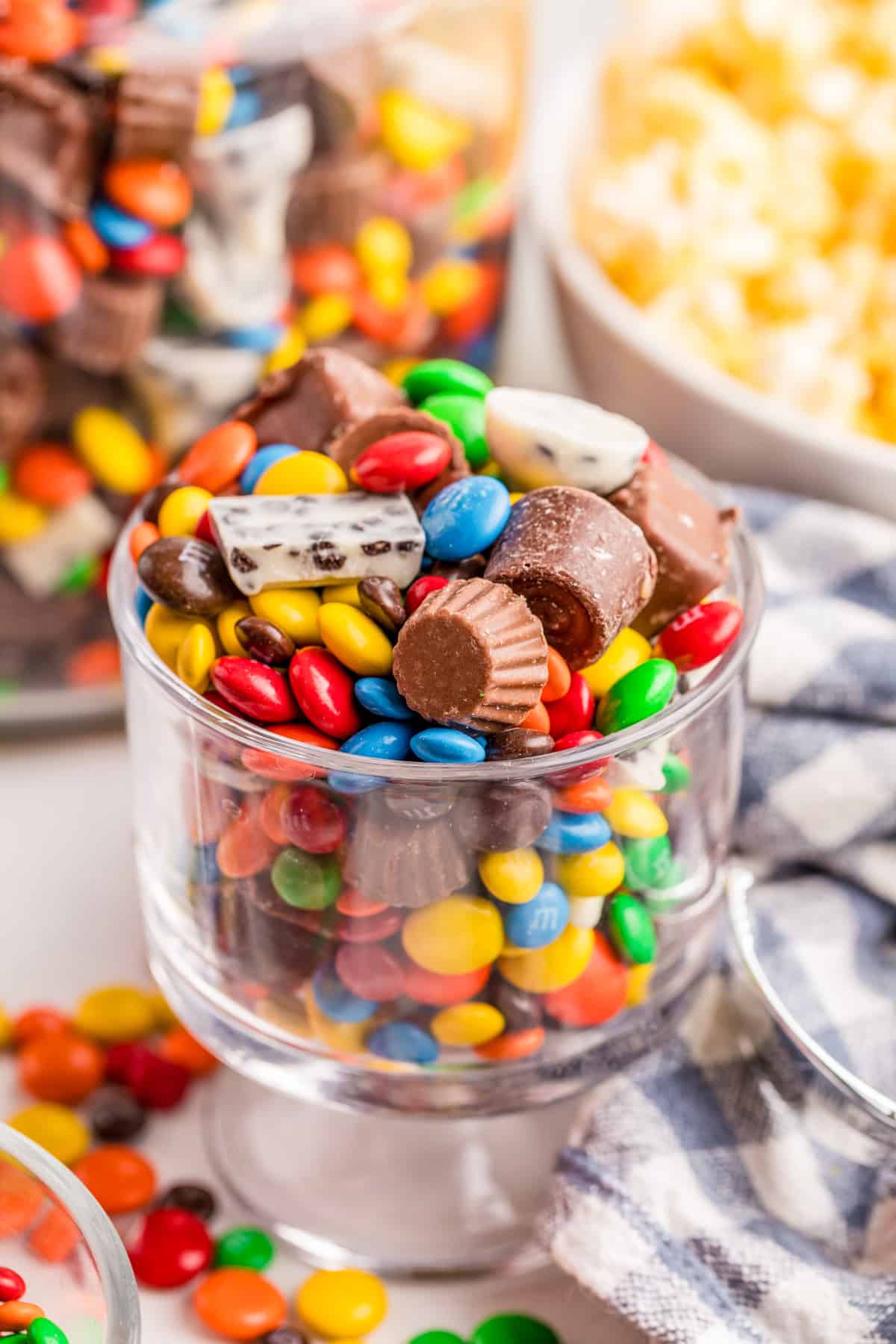 Chocolate Candy Salad in a small serving dish with large container and popcorn in background.