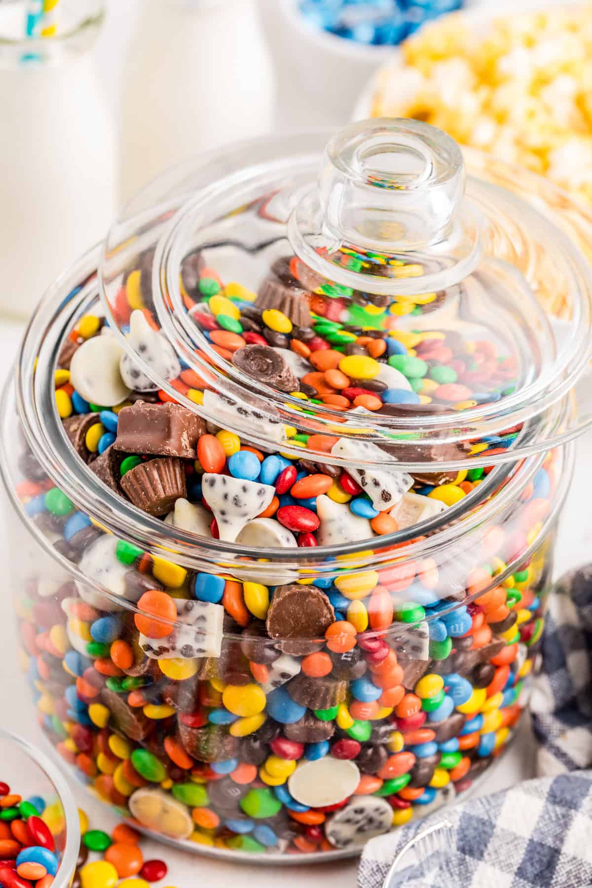 Salad in large glass container with the lid slightly off to the side with milk and popcorn in background.