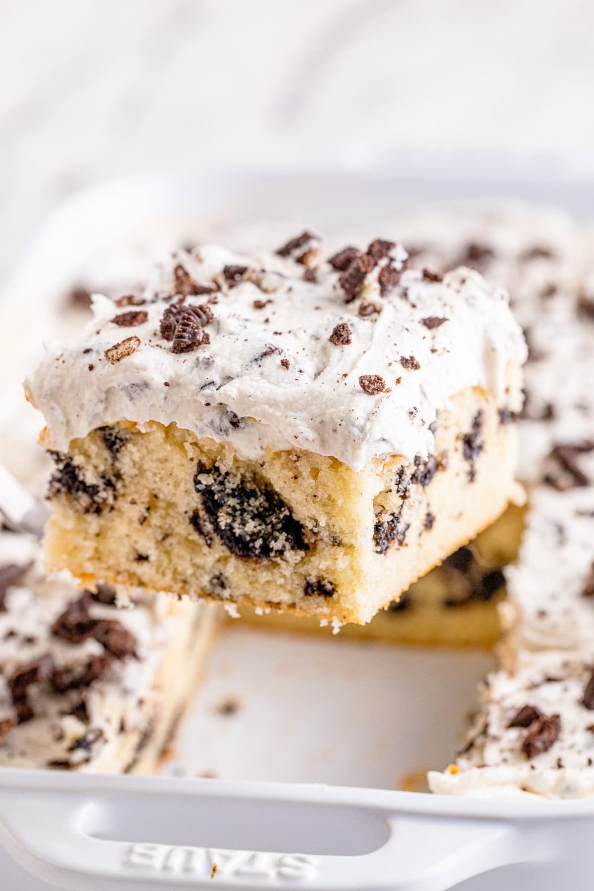 Cake server holding up one slice of Cookies and Cream Cake out of pan.