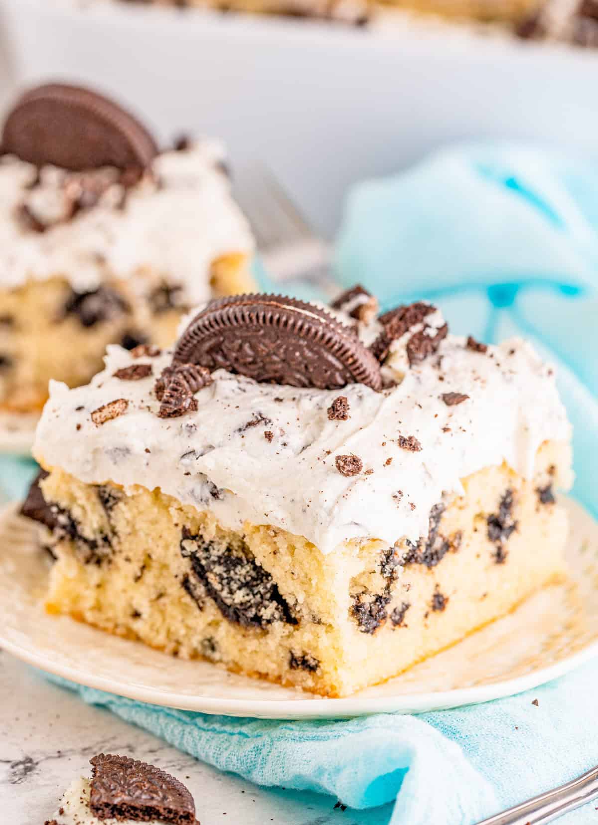 Slice of Cookies and Cream Cake on white plate topped with cookies.