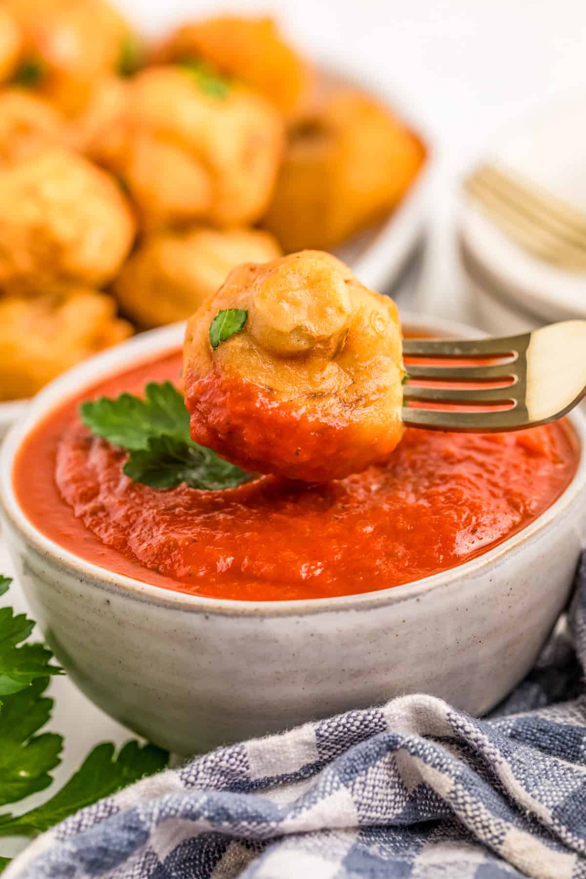 One mushroom being dipped into marinara sauce.