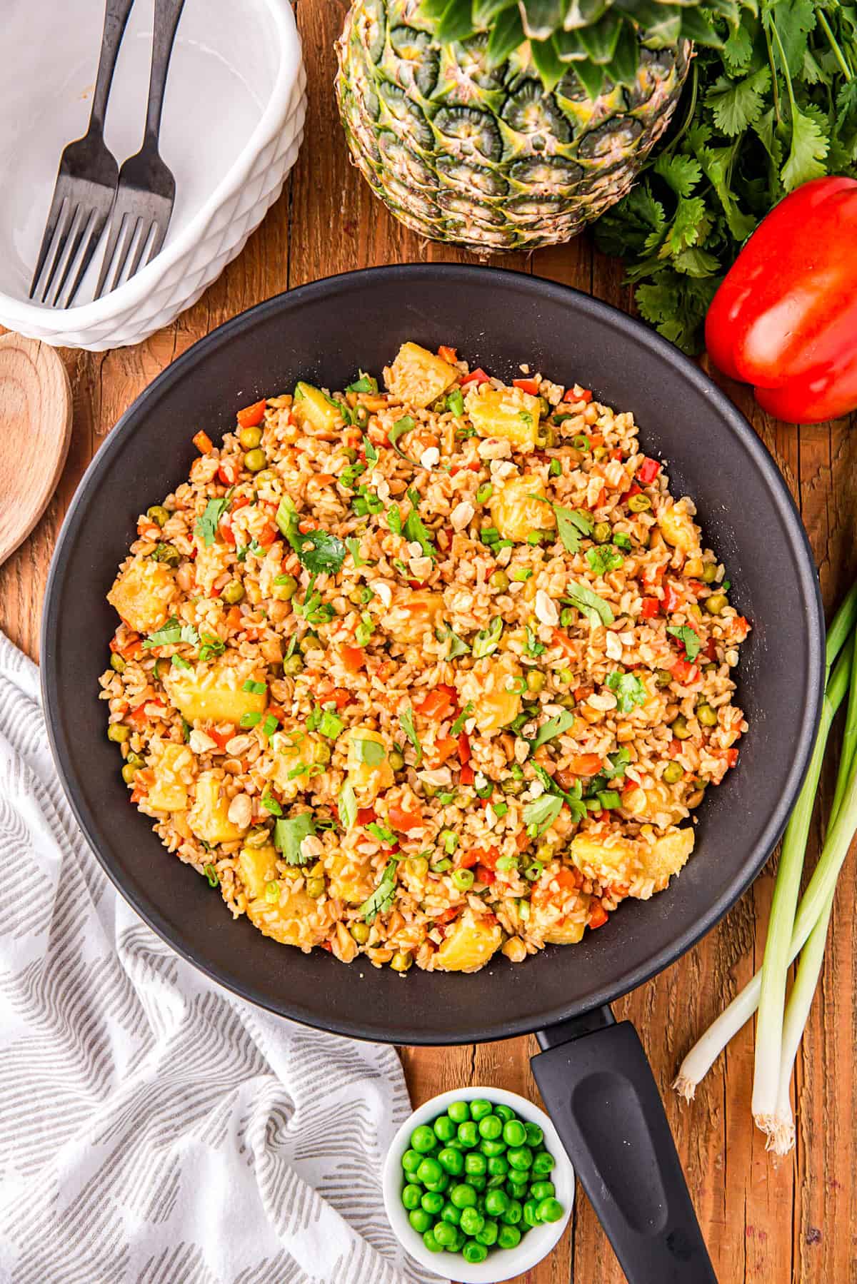 Overhead of finished Thai Pineapple Fried Rice in pan, surrounded by other ingredients.