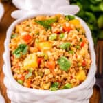 Close up square image of rice in a white pineapple shaped bowl.