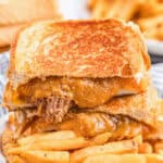 Close up square image of sandwich cut in half stacked on fries.