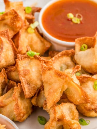 Close up square image of finished rangoon on plate garnished with dipping sauce.