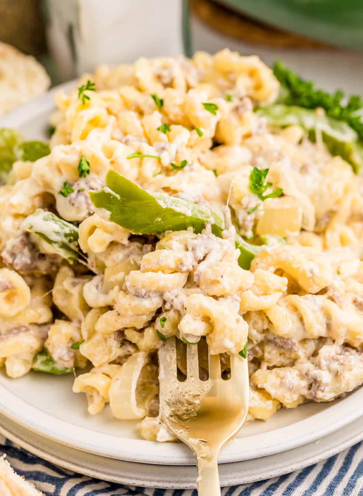 Close up of pasta on stacked white plates with a fork holding up some of the pasta.