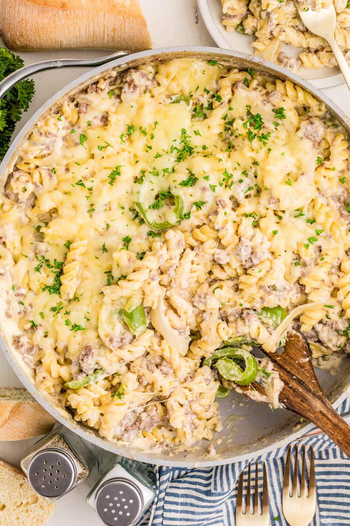 Overhead of Philly Cheesesteak Pasta in dish with serving spoon in it with some pasta scooped out.