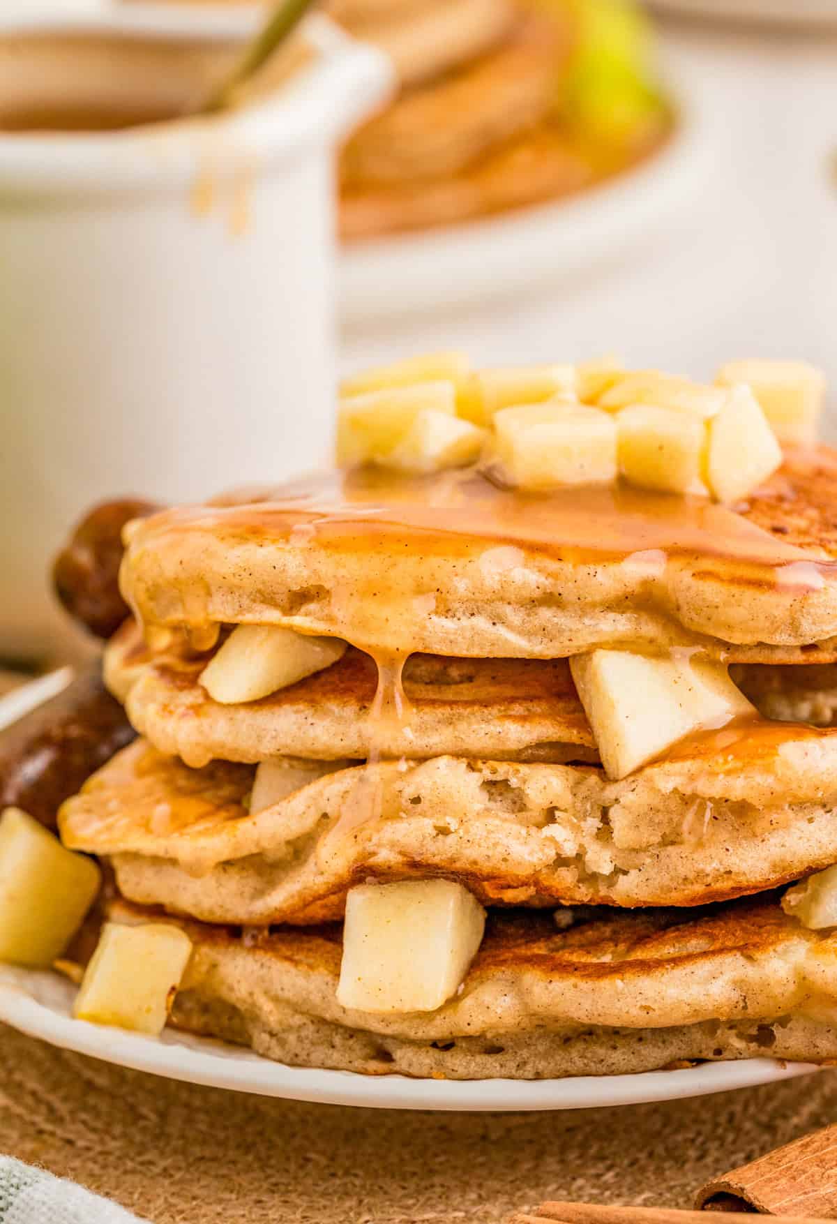 Close up side view of the Apple Pancakes stacked with diced apples and syrup.