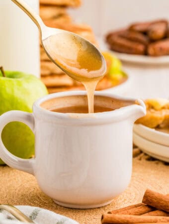 Square image of white spouted cup with spoon ladeling syrup out of cup.