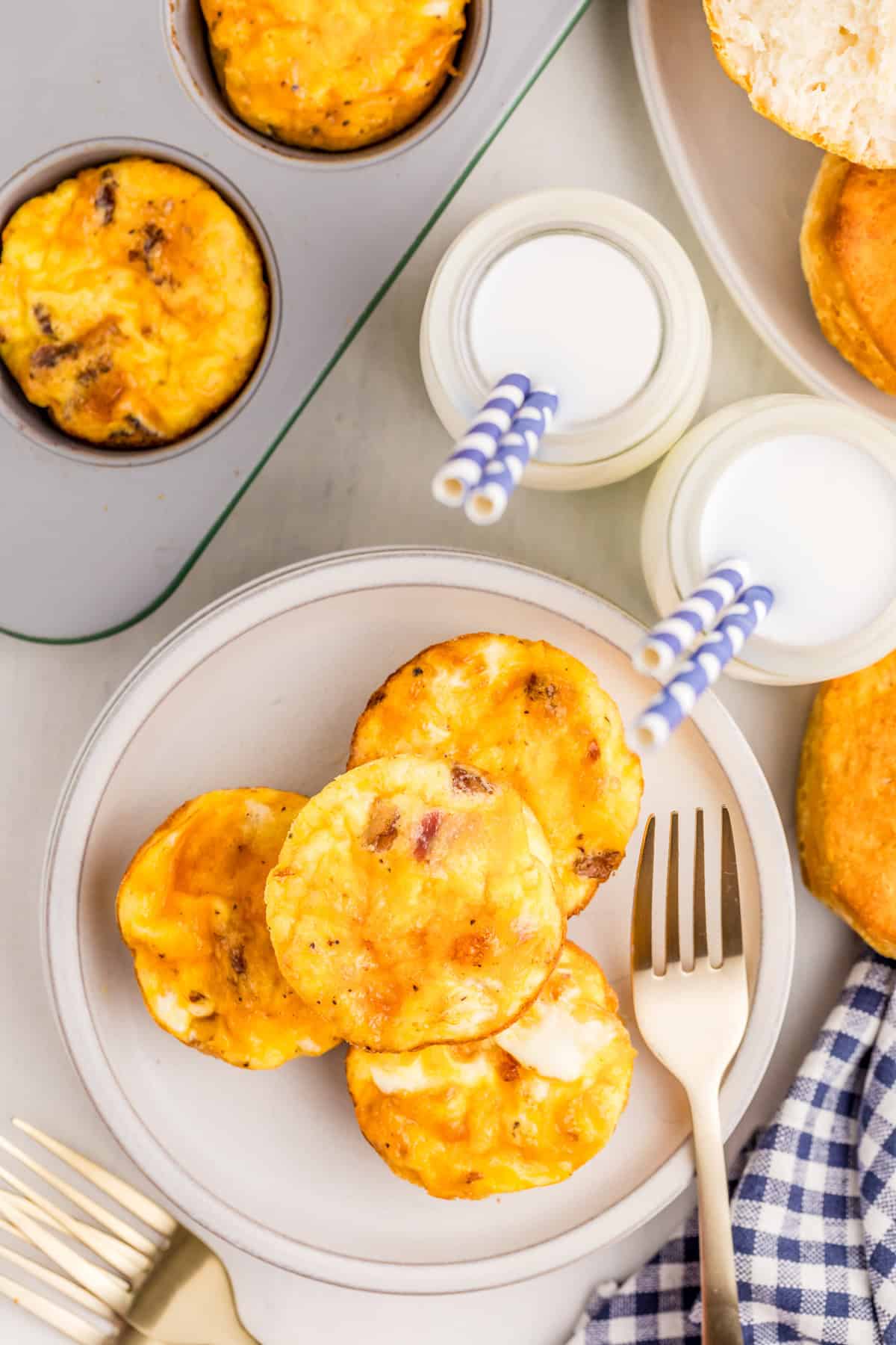 Overhead of stacked bites on white plate with milk and pan of bites next to it.