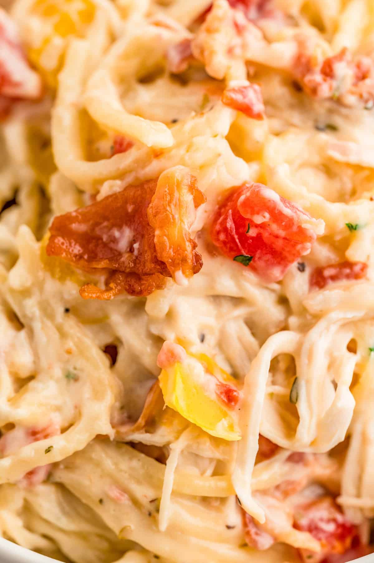 Very close up photo of spaghetti showing the creaminess and ingredients.