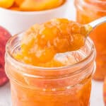 Close up square image of jam on spoon being taken out of a mason jar.