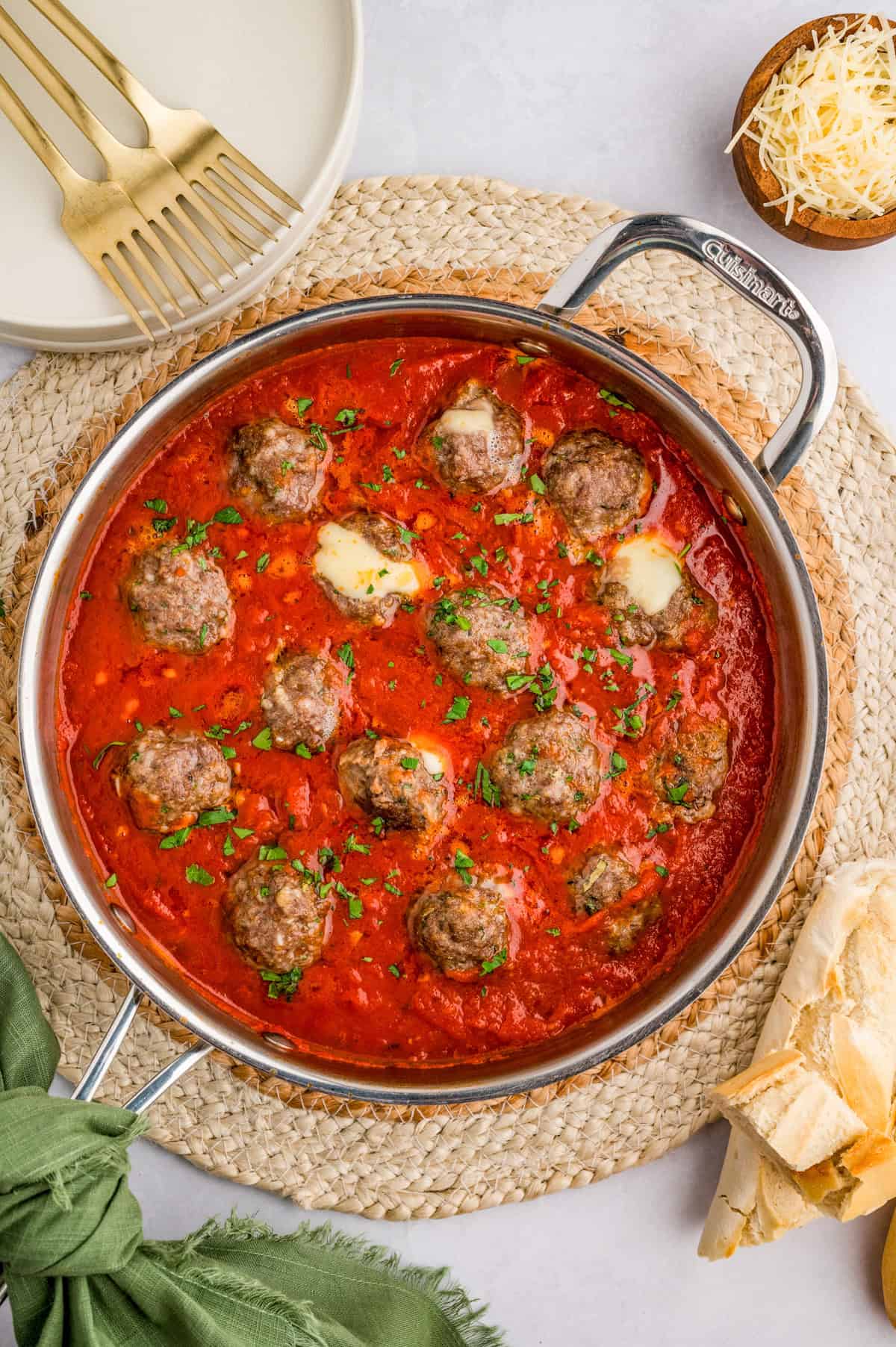 Overhead of Mozzarella Stuffed Meatballs in pan in sauce with cheese oozing out of some meatballs.