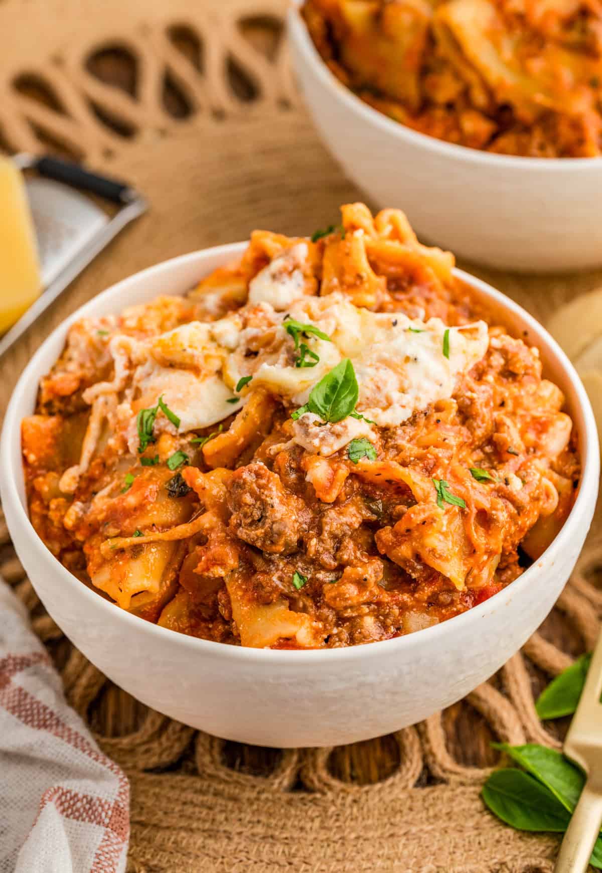 Skillet Lasagna served in white bowl topped with cheese and basil.