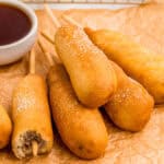 Close up of stacked corn dogs on parchment paper.