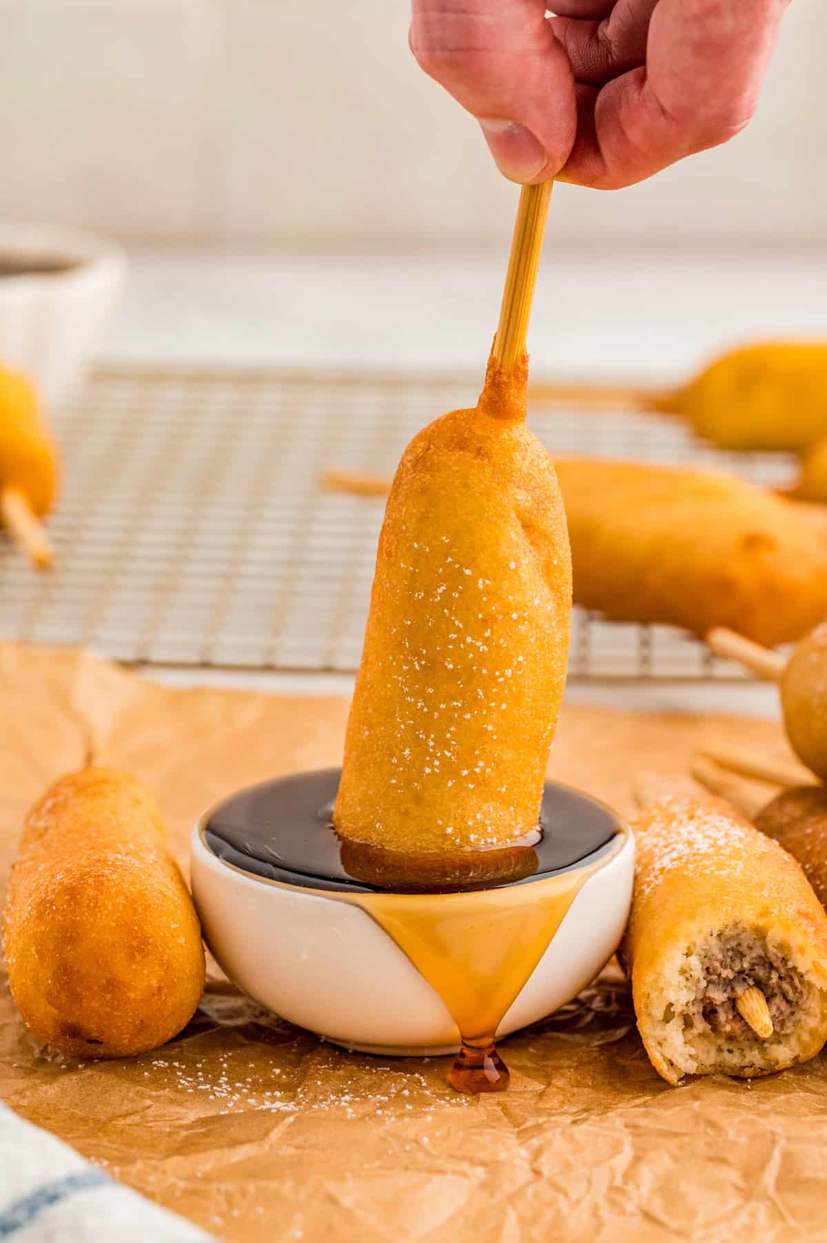 Hand dipping one of the corndogs in syrup.