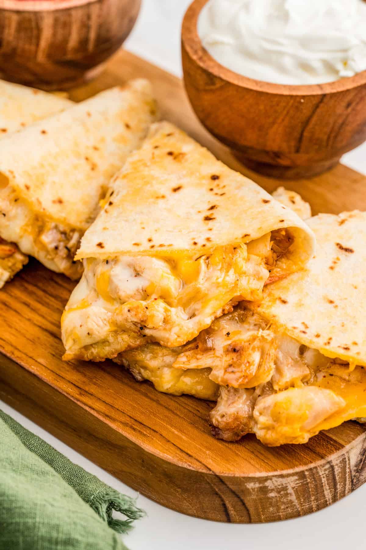 Chicken Quesadilla Recipe cut into triangles on wooden board.