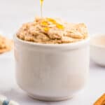 Close up square image of butter in white bowl being drizzle with honey.