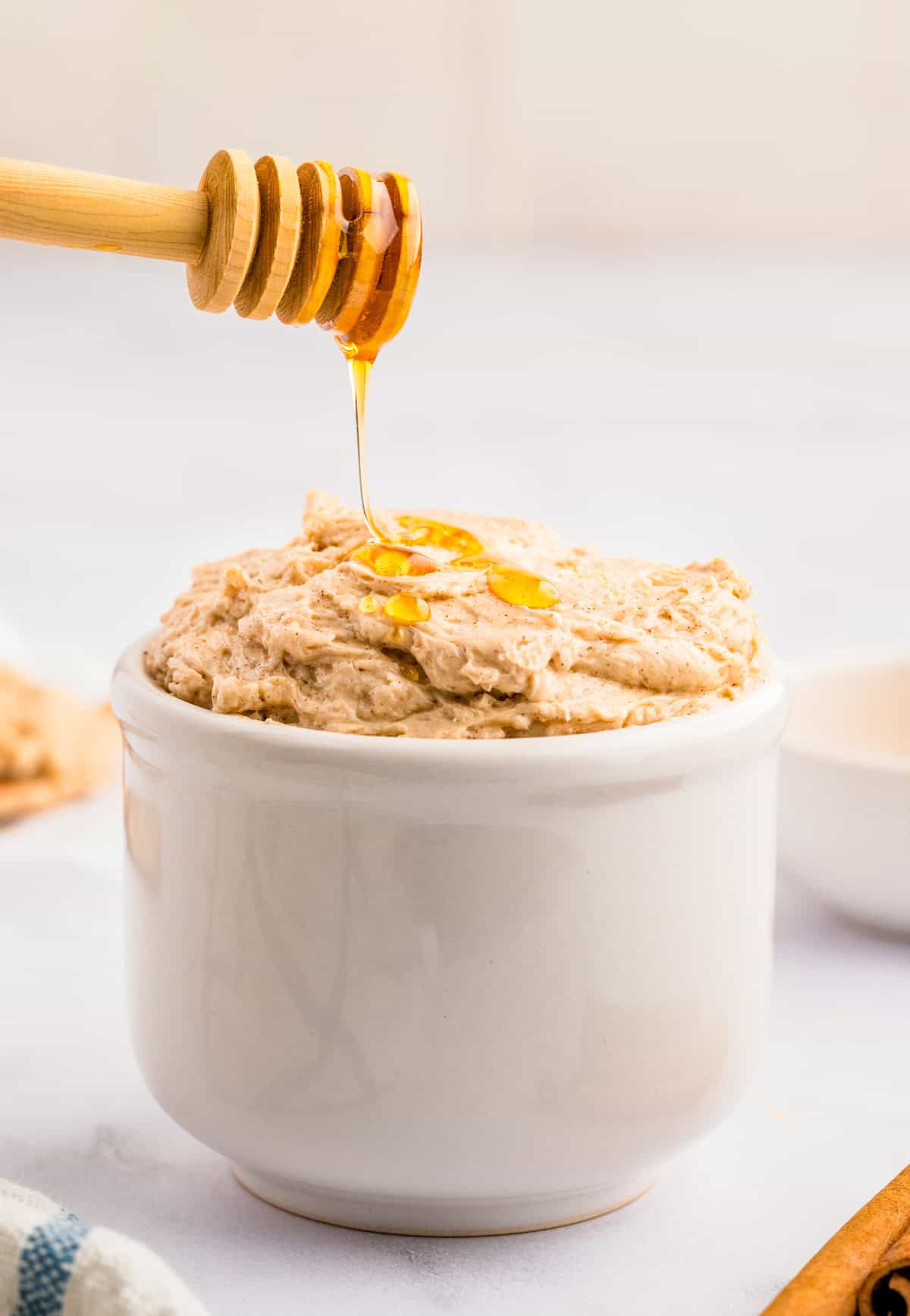 Cinnamon Honey Butter in white bowl being drizzled with honey.