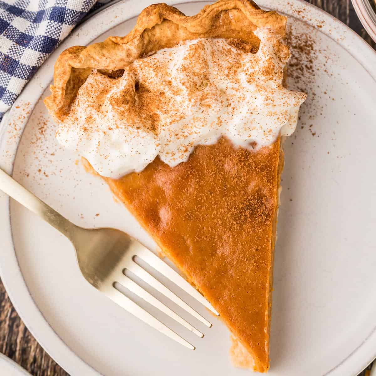 Overhead square image of a slice of pie on white plate with fork garnished.