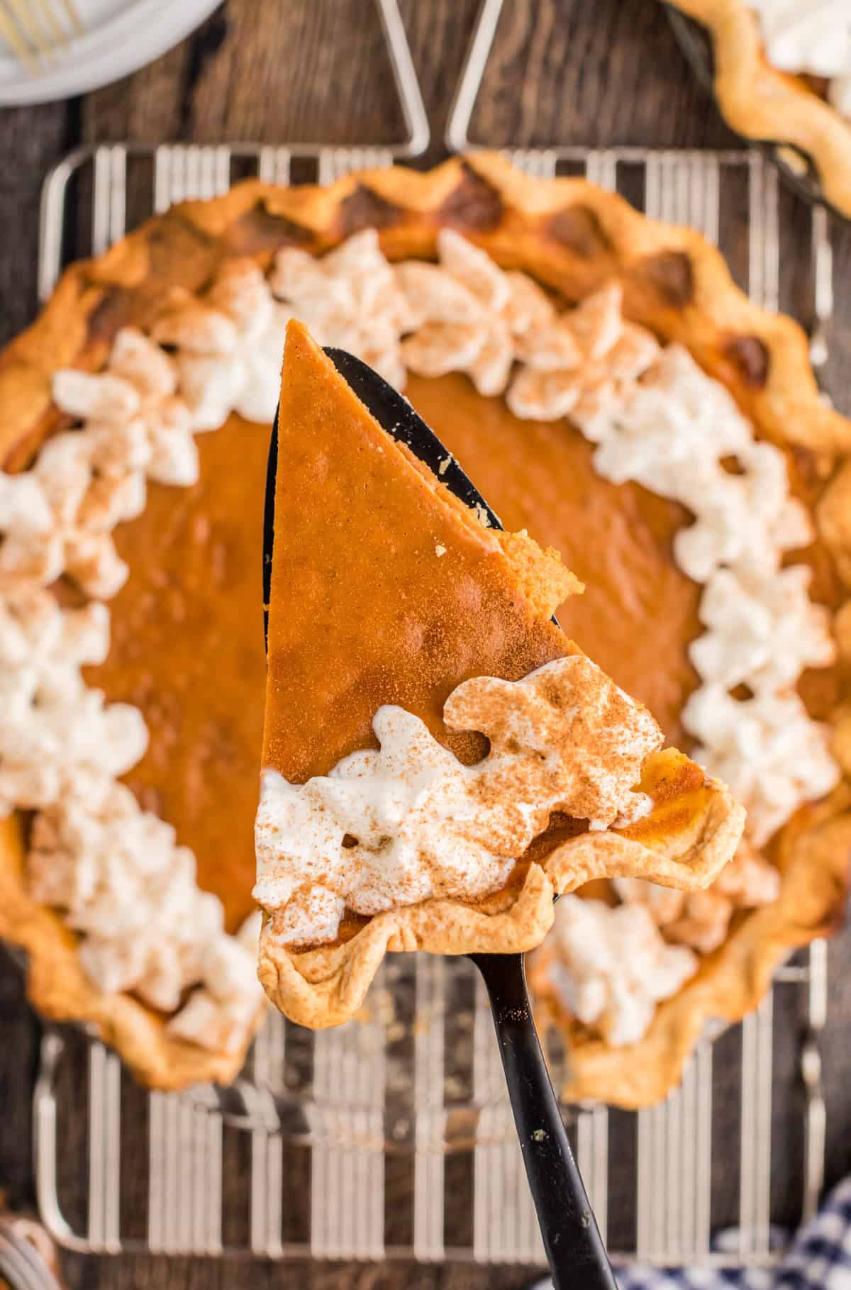 Overhead of a pie server holding up a slice of the Easy Pumpkin Pie out of the pie plate.