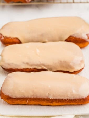 Square image of three donuts on white tray.