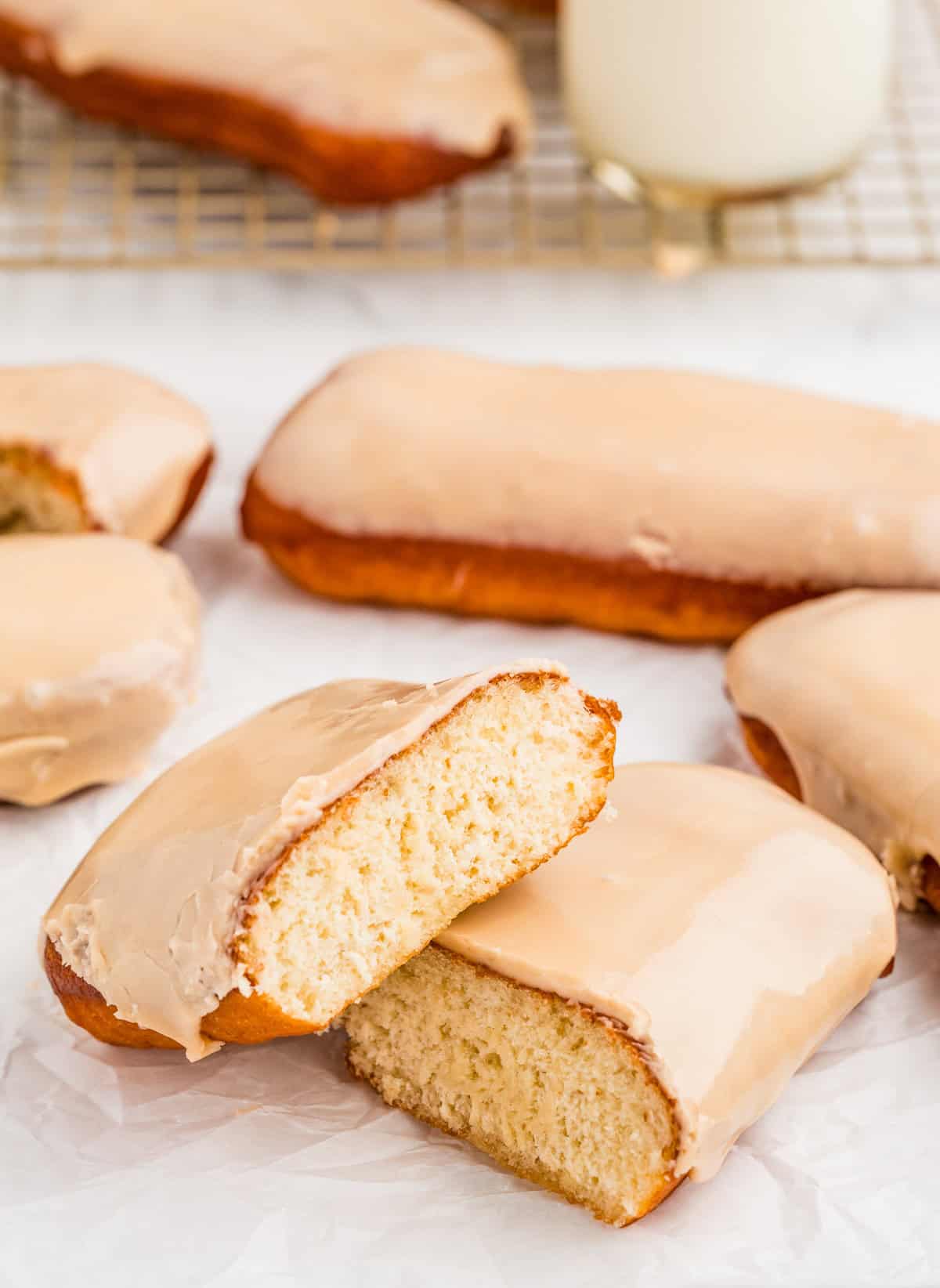 One of the donuts cut in half on parchment paper with more donuts in background.