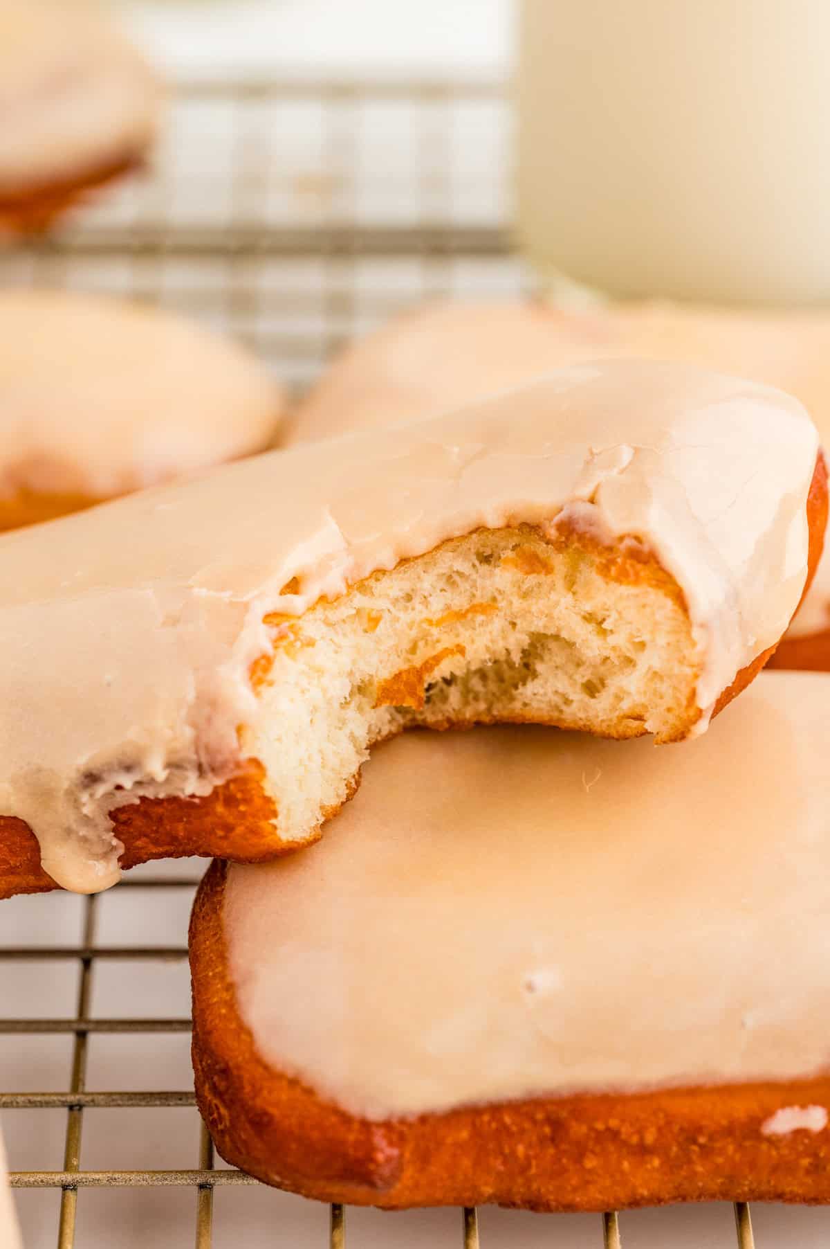 Closeup of bite of donut showing the fluffy outside on top of another donut.