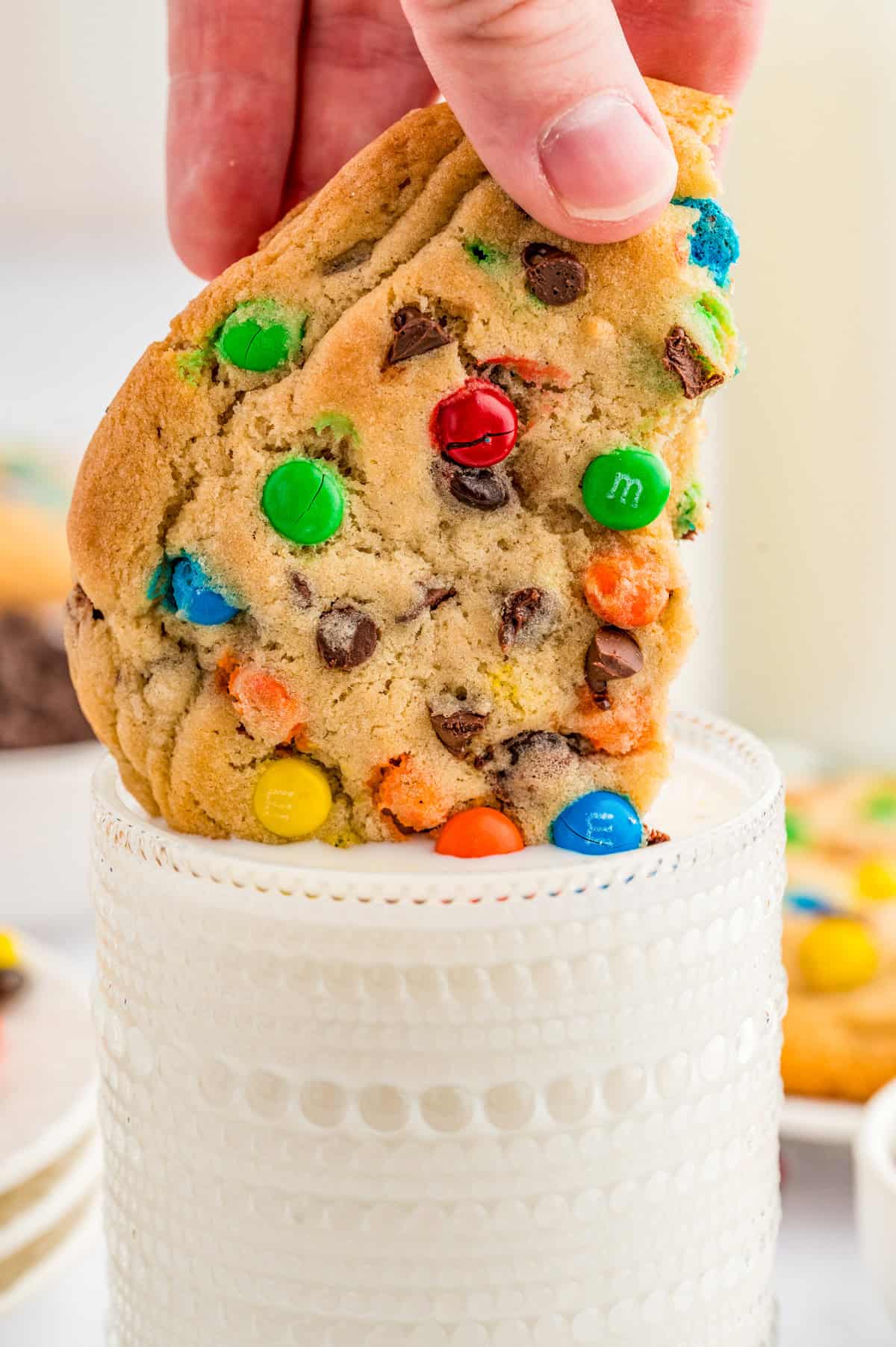 Hand dunking half a cookie in a glass of milk.