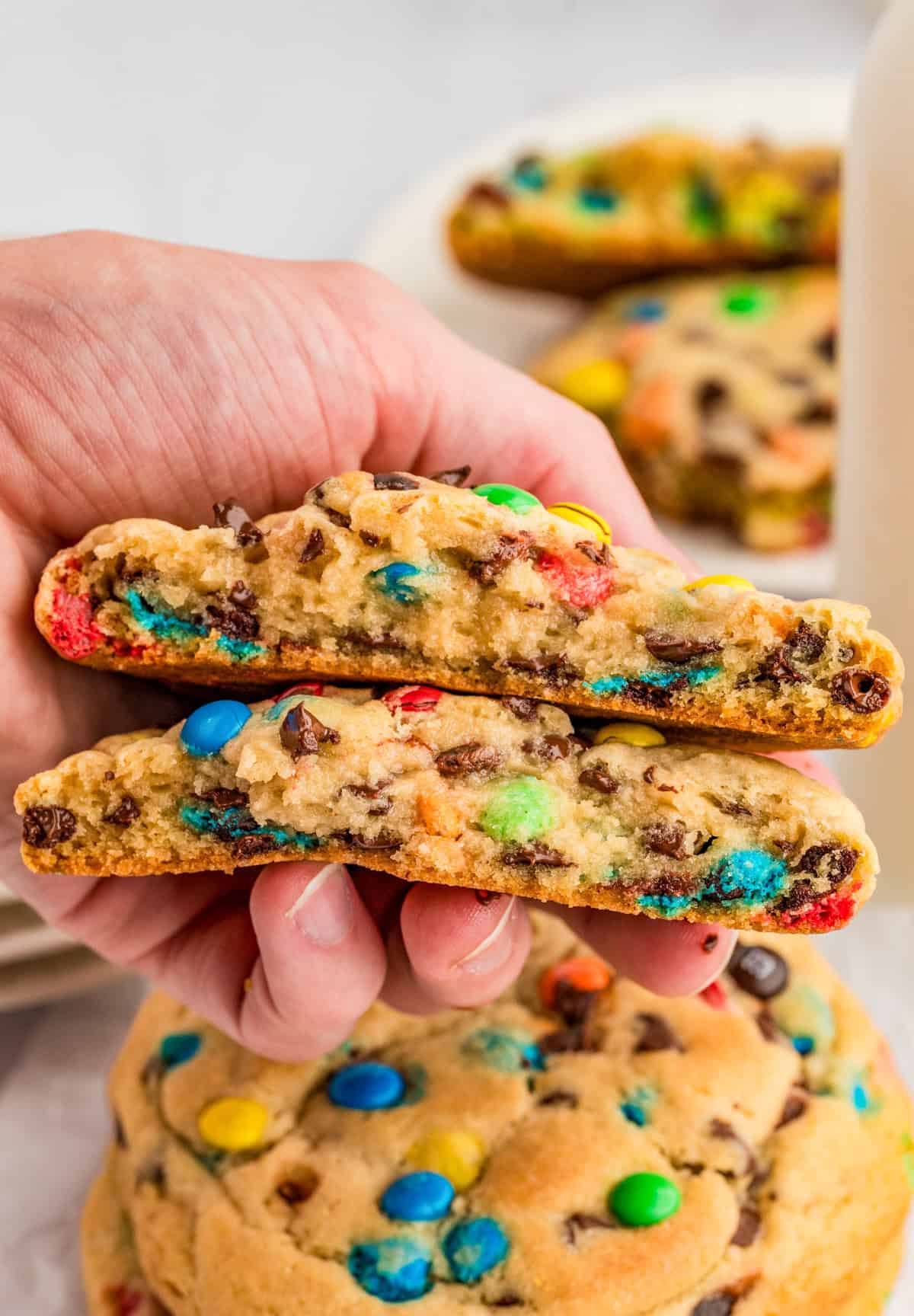 Hand holding one cookie split in half showing the chewy inside.