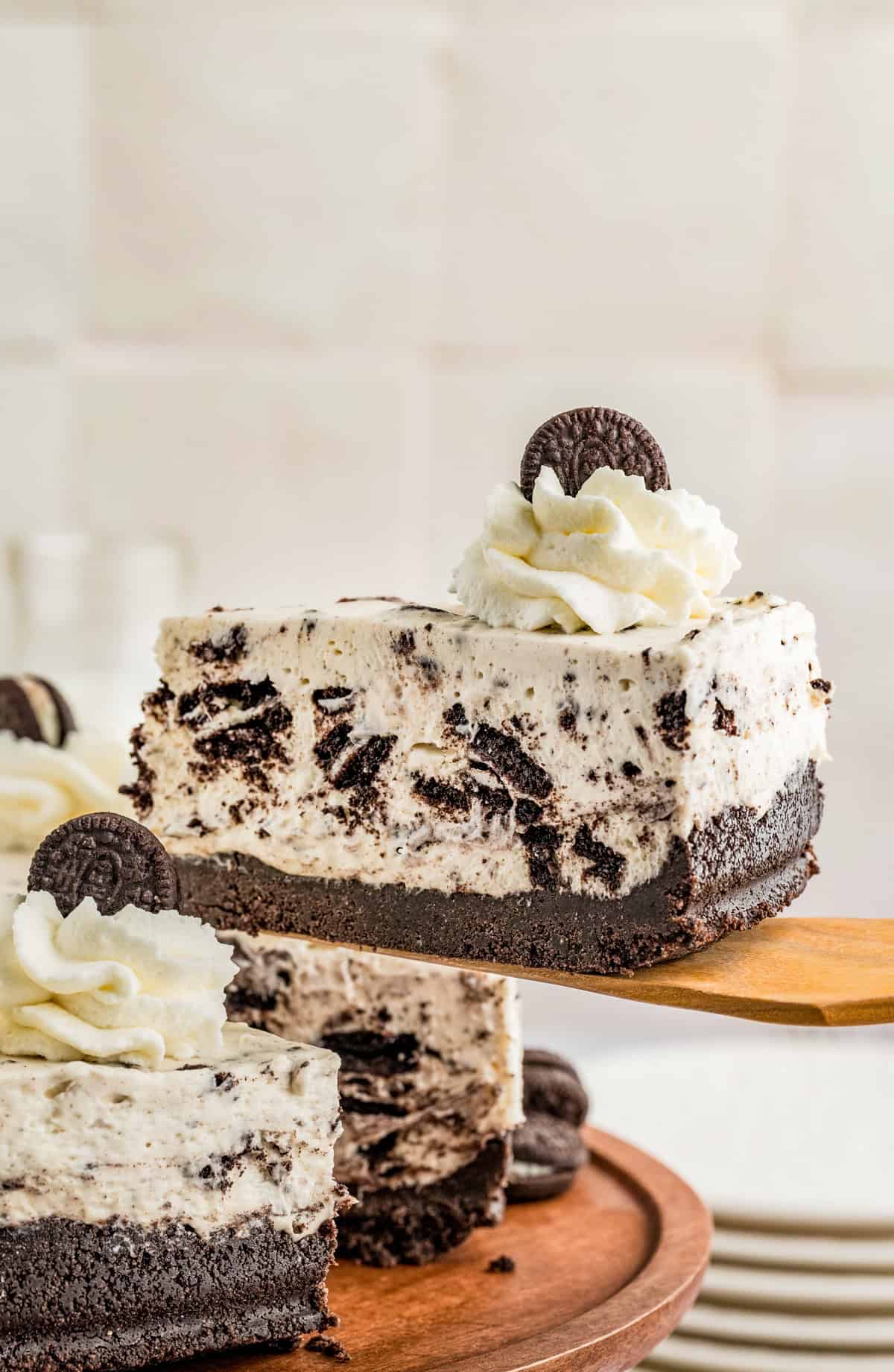 Slice of cheesecake being held up by wooden cake server.