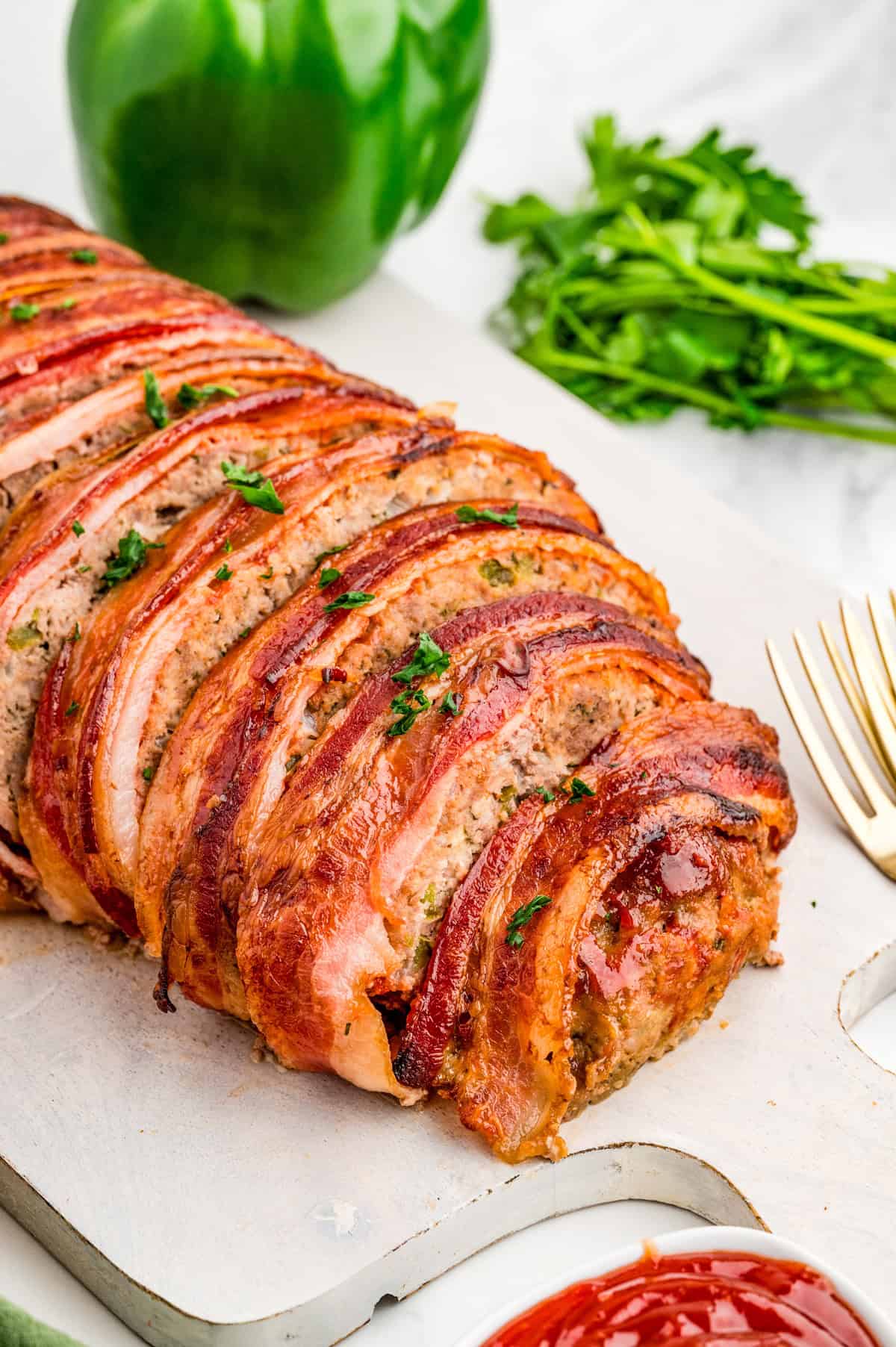 Finished Bacon Wrapped Meatloaf sliced on white board.