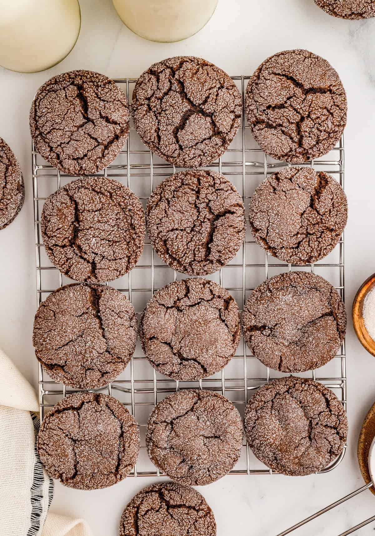 Overhead of cookies on wire rack with milk in background.