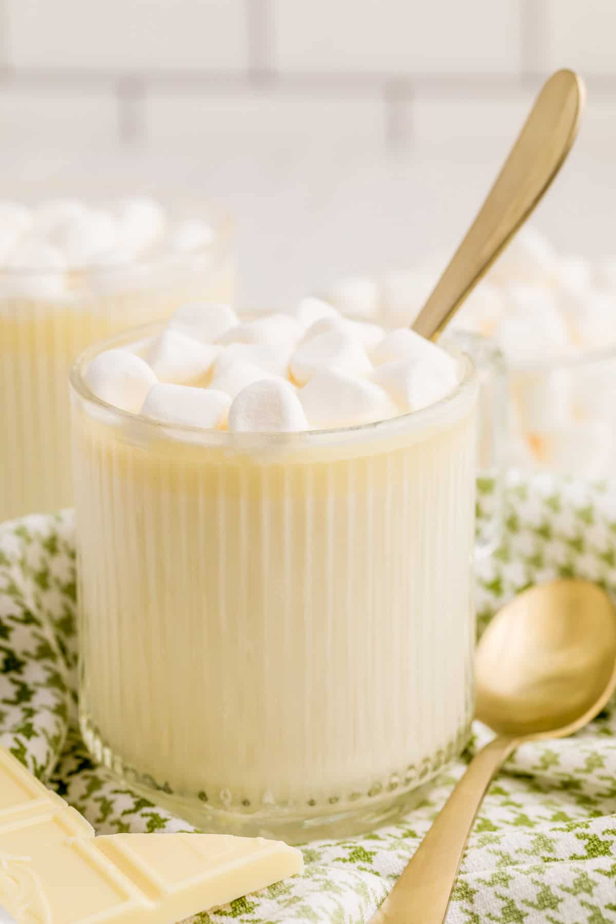 Hot Chocolate in clear ribbed mug with spoon in mug topped with marshmallows.