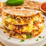 Close up square image of tacos stacked on white plate.