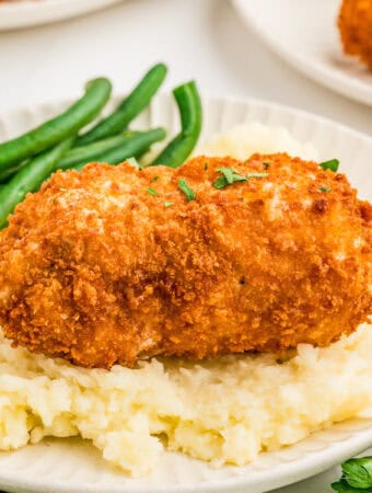 Square image of chicken topped with parsley over mashed potatoes.