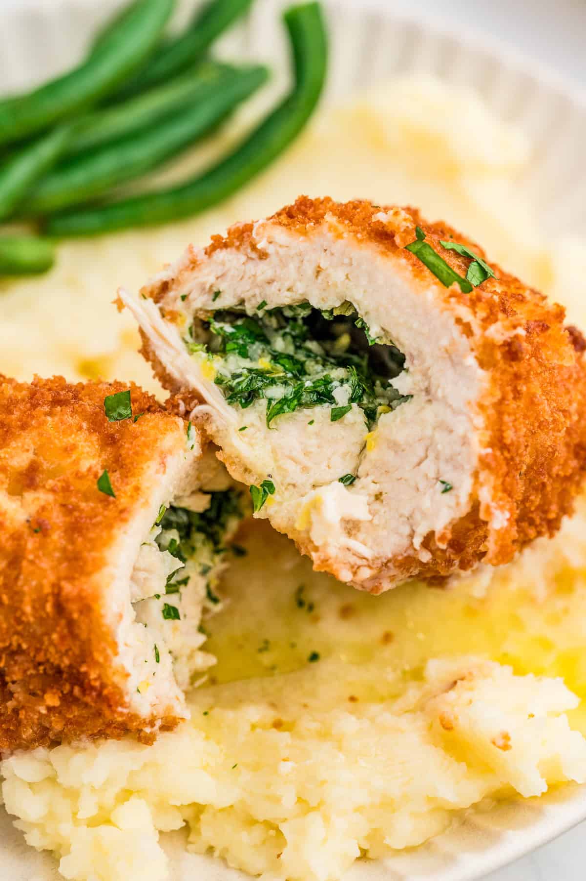 Chicken Kiev cut in half leaning against other half showing the butter inside.