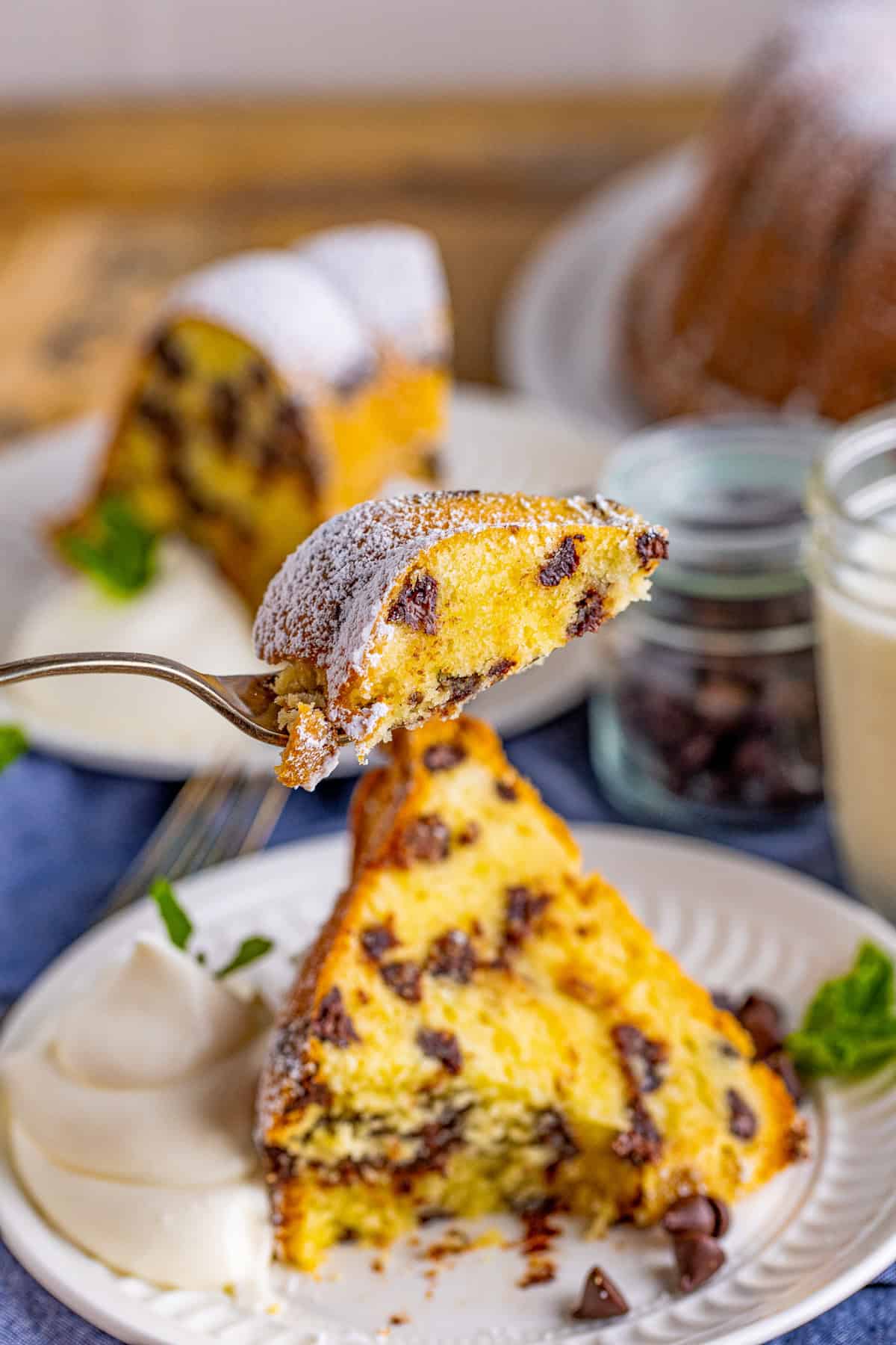 Fork holding up a bite of cake from a slice from plate.