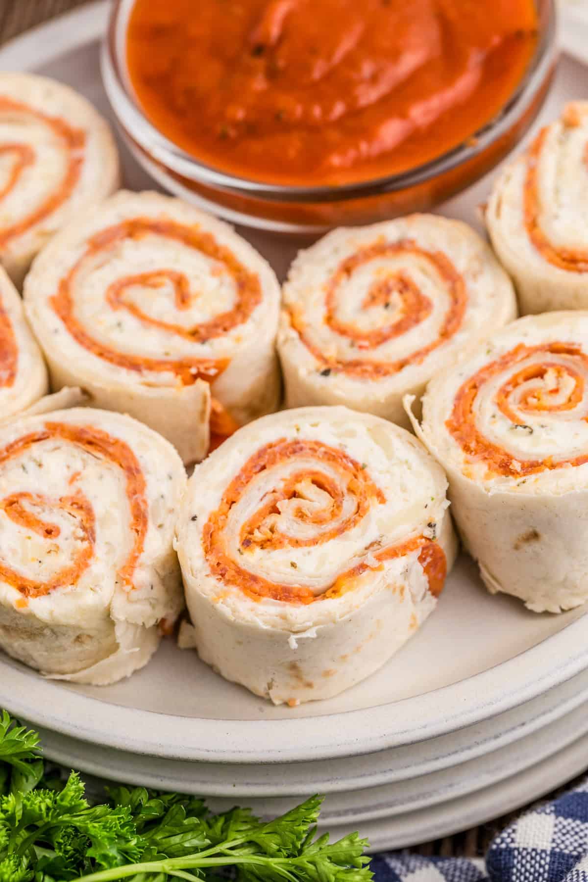 Pinwheels on white plate with pizza sauce for dipping/